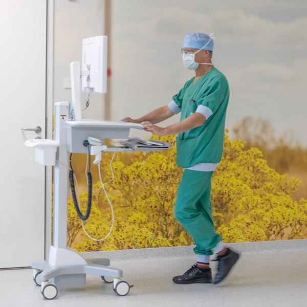 Hospital caregiver pushing a MediPod Power workstation in a corridor